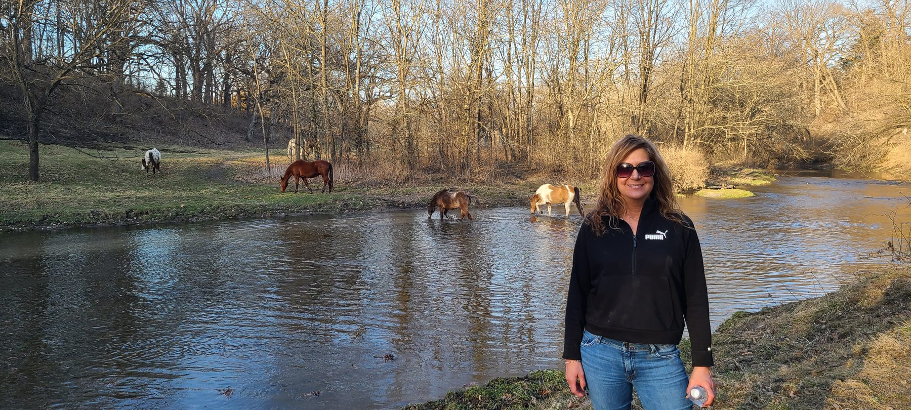 Amanda Tremper near a creek with horses grazing